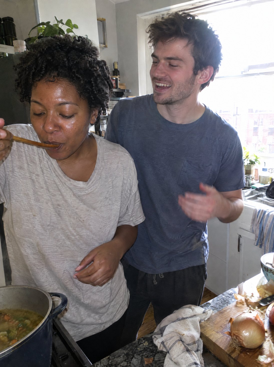 A couple cooking together in a sunlit kitchen